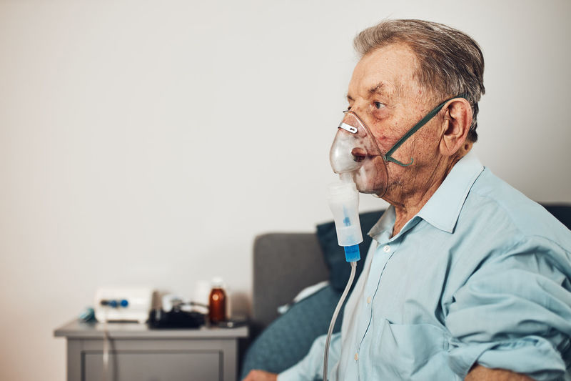 Senior man inhaling airways and lungs applying medicine. covid-19 or coronavirus treatment