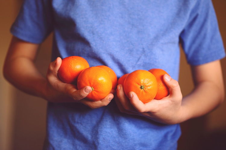 Midsection of man holding oranges