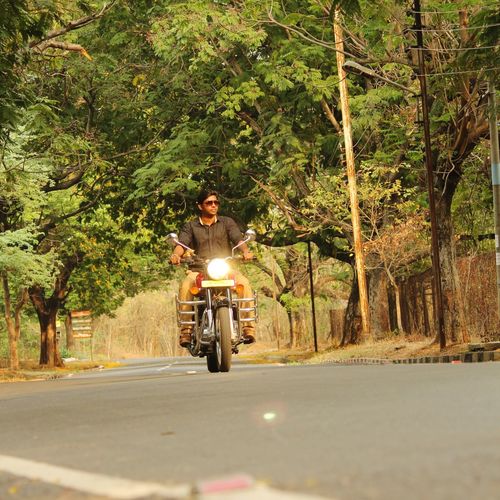 Young man riding motorcycle on road in forest