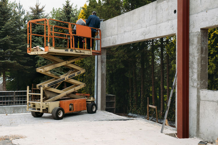 Scissor lift platform with workers on a construction site. building concreate house with mobile