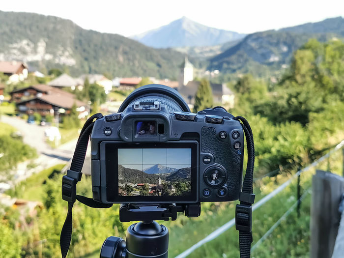 Close-up of camera on landscape against mountain range
