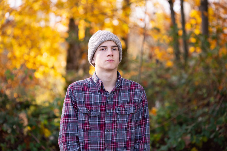 Portrait of young man standing against trees during autumn