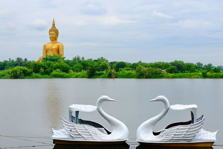 Buddha statue by lake against sky