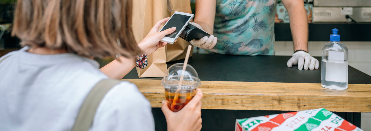 Woman making contactless payment through smart phone at restaurant