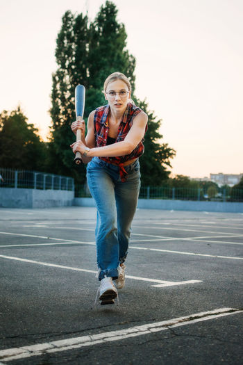 Girl power, feminism, women self-defense. portrait of woman with baseball bat on parking outdoor