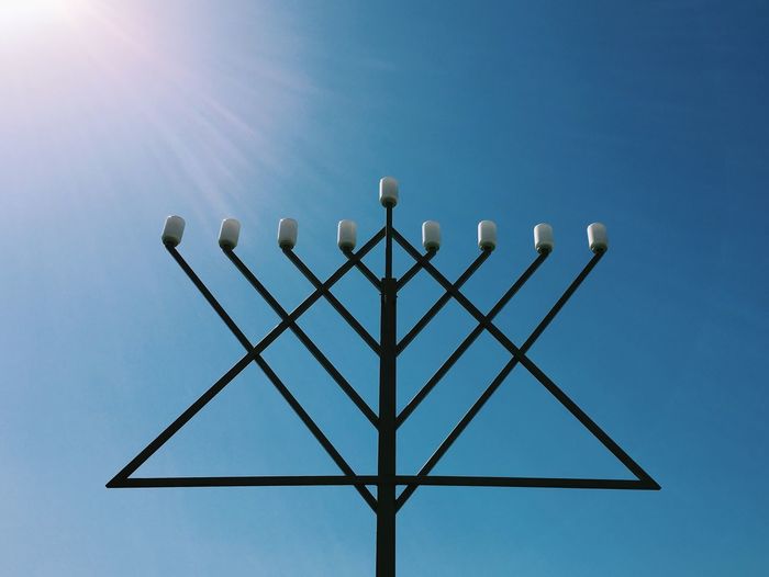 Low angle view of menorah against clear sky on sunny day