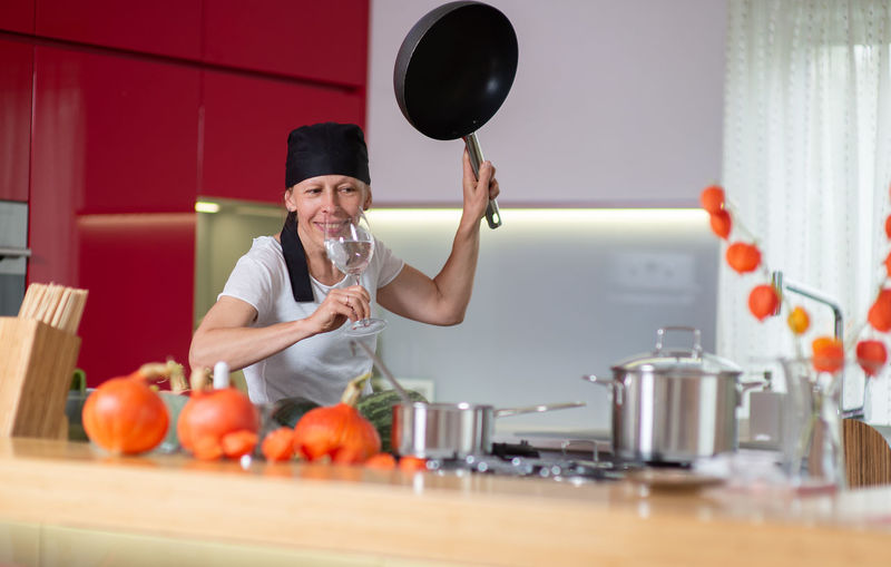 Woman having drink while making food at home