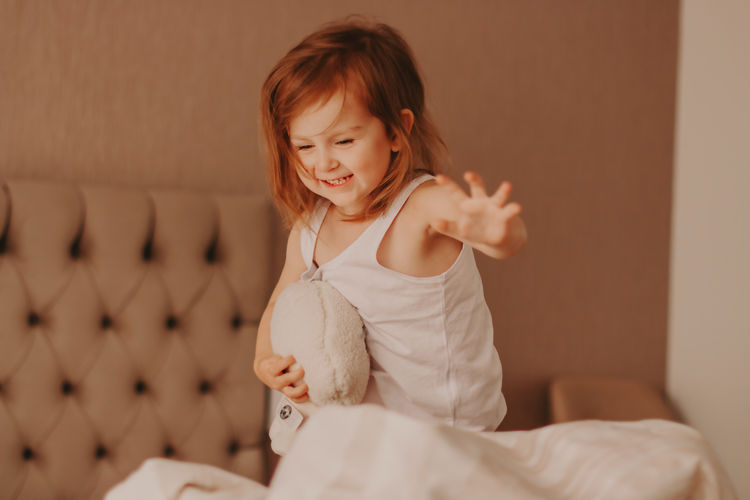 Cute little girl enjoying early morning on bed at home