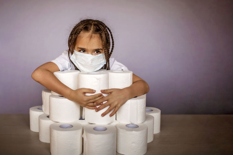 Close-up of girl wearing mask with toilet paper on table