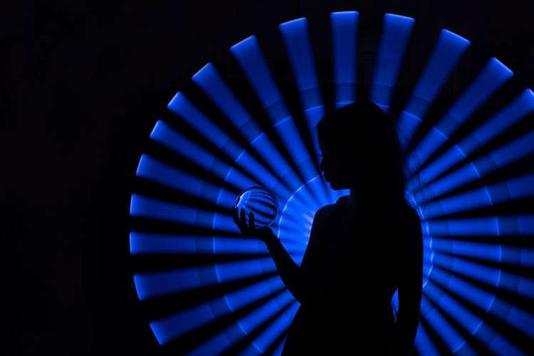 SILHOUETTE MAN STANDING AGAINST ILLUMINATED LIGHT