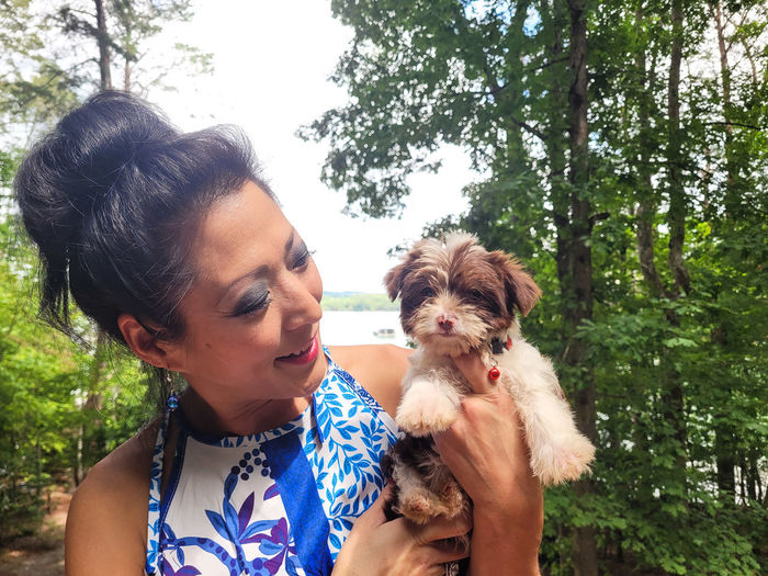 Asian lady holds new puppy at lake.