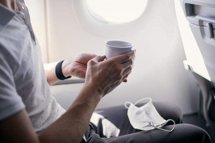 Passenger with face mask drinking coffee in airplane. themes traveling during pandemic covid-19.
