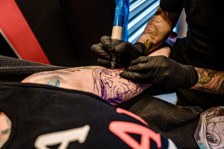 Close-up of artist tattooing design on human skin