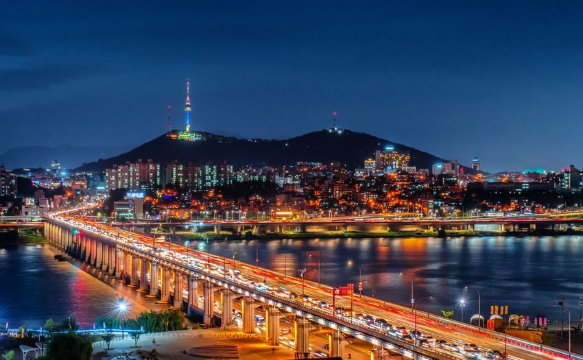 Illuminated bridge over river in city at night