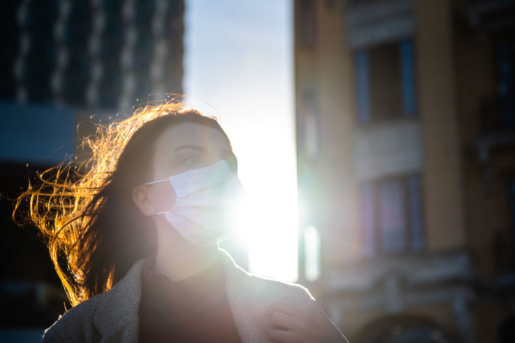 Woman wearing mask on road against buildings