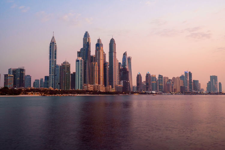 Modern buildings in city by sea at dusk