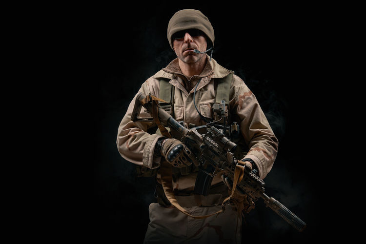 Man holding rifle against black background