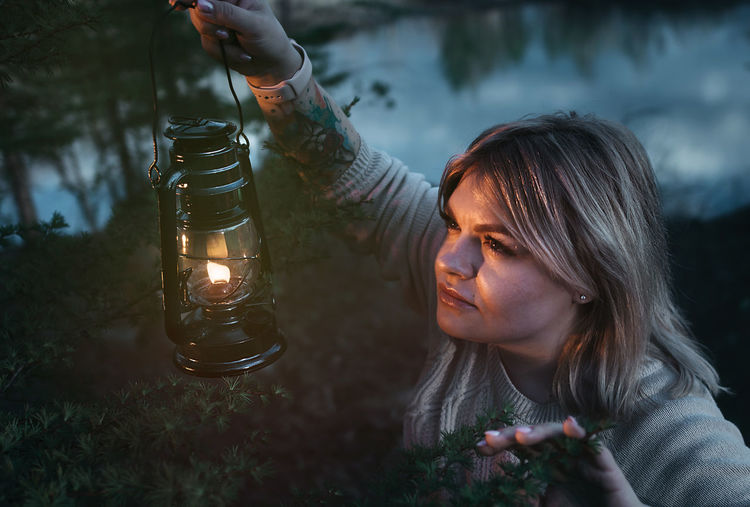 Young woman looking away while holding illuminated oil lamp