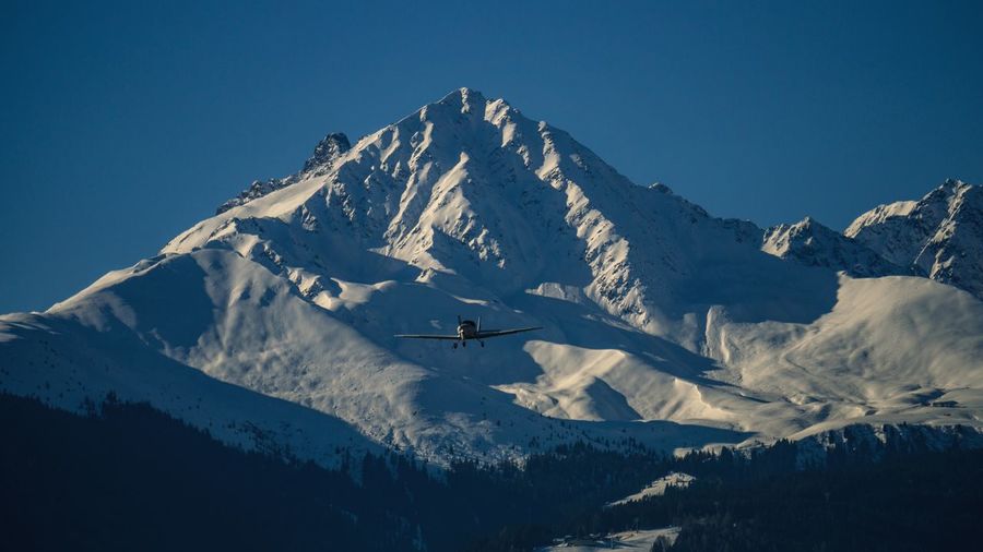 Airplane flying against snowcapped mountain