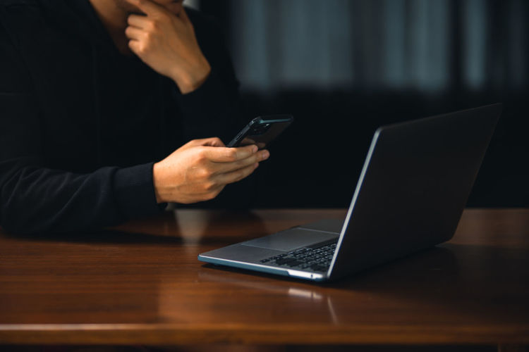 Midsection of woman using mobile phone on table