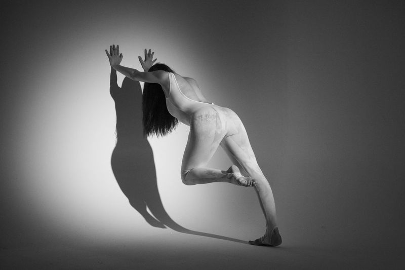 Side view of naked woman against black background