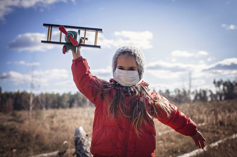 Girl wearing respirator masks staying in forest with toy air plane, guideline in quarantine time