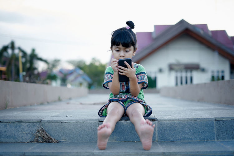 Full length of girl using phone against clear sky