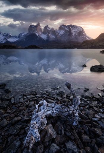 Scenic view of lake and snowcapped mountains against sky during sunset