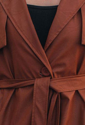 Street style fashion details of autumn trench, leather long stylish brown coat. female outfit.