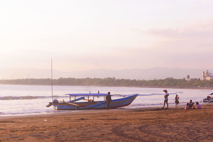 Fishermen with their boats on the beach to sunset