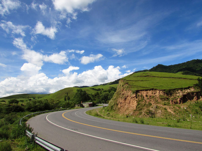 Scenic view of road by mountain against sky