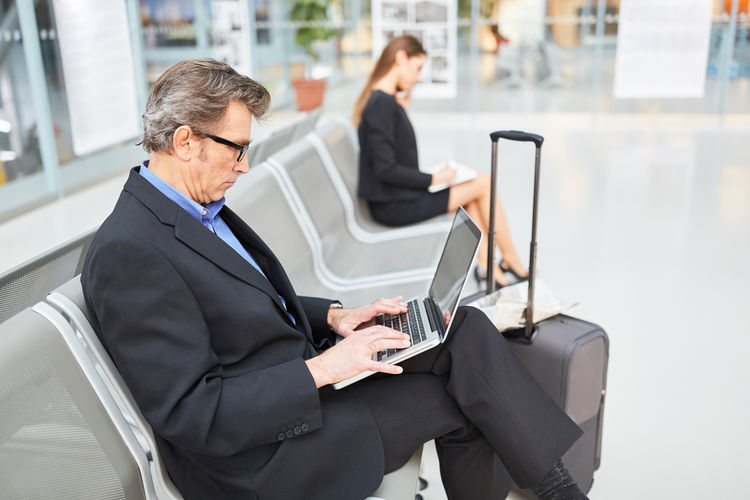 Business people working while sitting on chair at airport