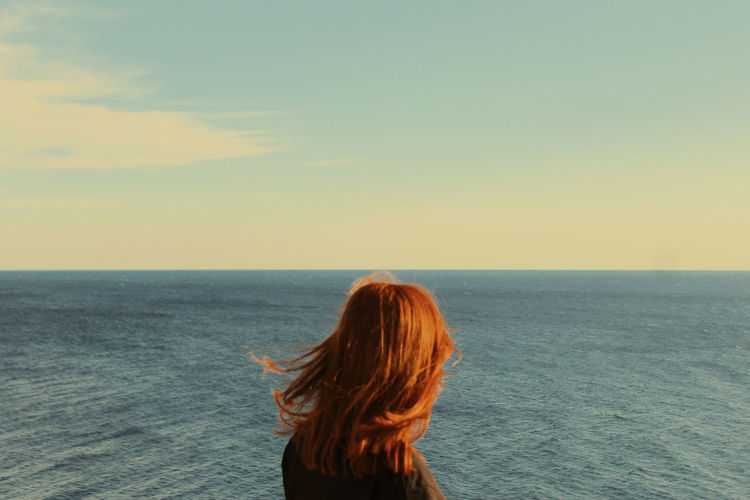 Rear view of woman looking at sea against sky