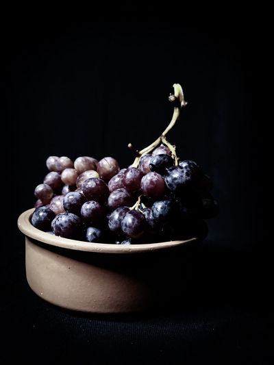 Close-up of grapes in bowl against black background