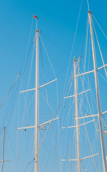 Silhouettes of match yachts in the marina against the backdrop of a clear blue sky, vertical frame