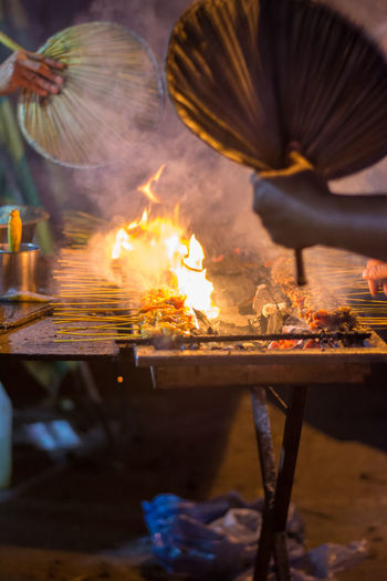 Cropped image of men preparing satay at market stall