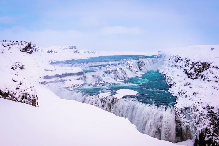 Scenic view of frozen waterfall against sky