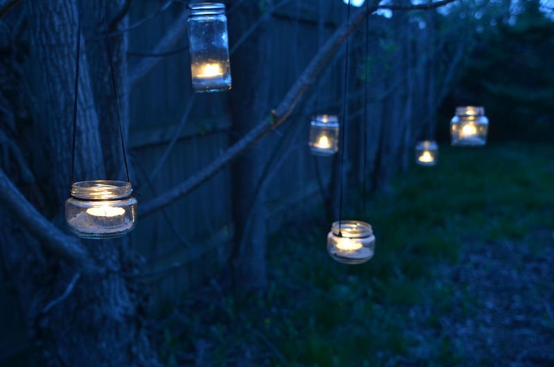 Night scene with candles in jars hanging from tree branches
