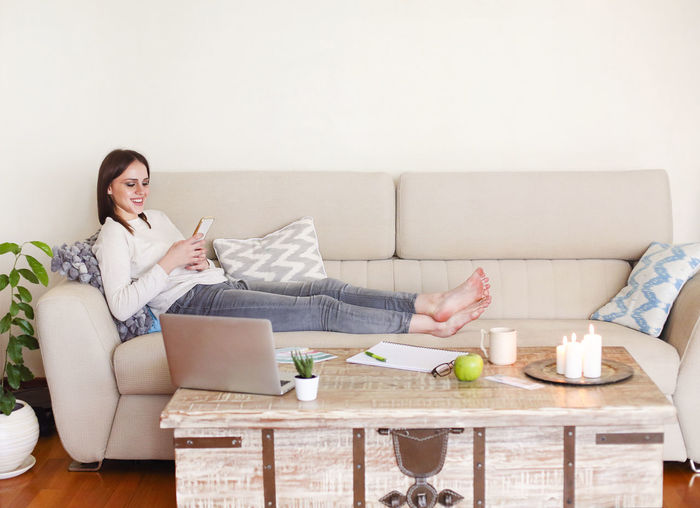 Woman using mobile phone while sitting on sofa