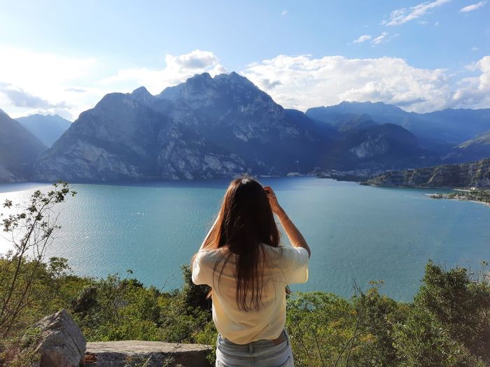 Girl taking photo of lake and mountains. 