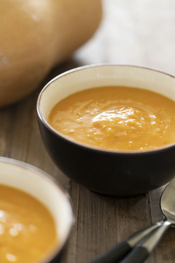 A view of bowl with delicious pumpkin soup and spoons on a wooden table