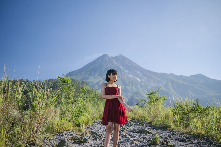 Full length of woman standing on rocks against mountain