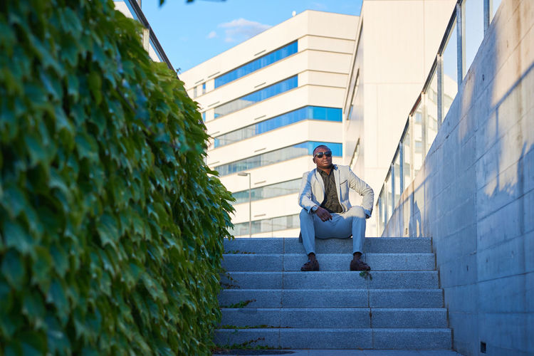 Low angle view of man sitting on staircase against building