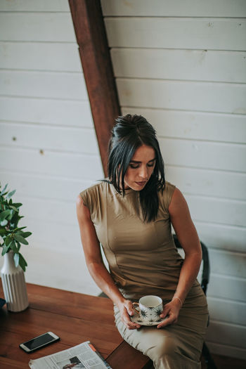 Woman drinking coffee while sitting on table