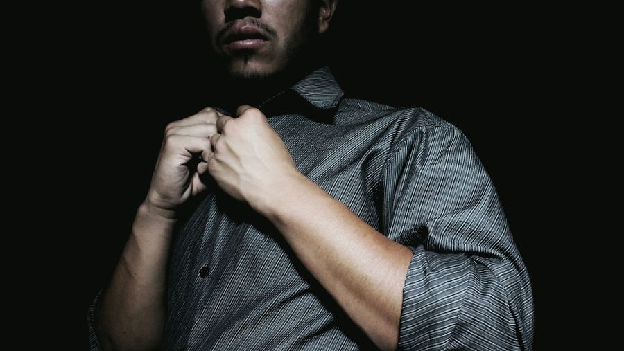 Close-up midsection of man wearing gray shirt against black background