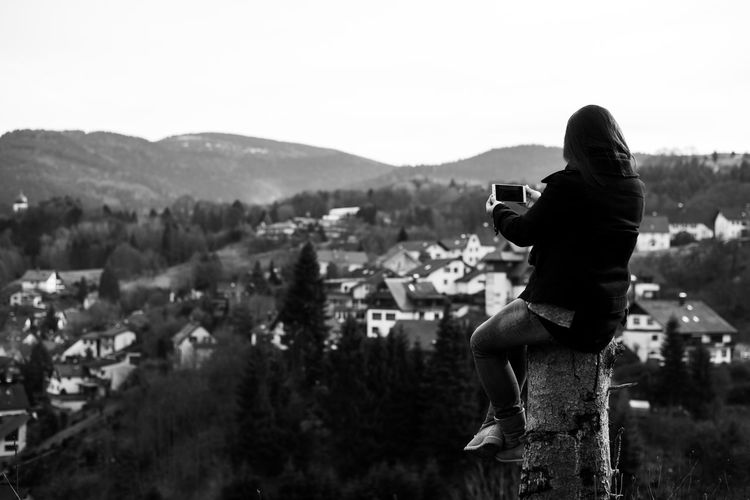 Full length of woman photographing cityscape against clear sky