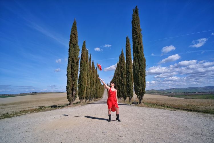Full length of woman standing on land against blue sky