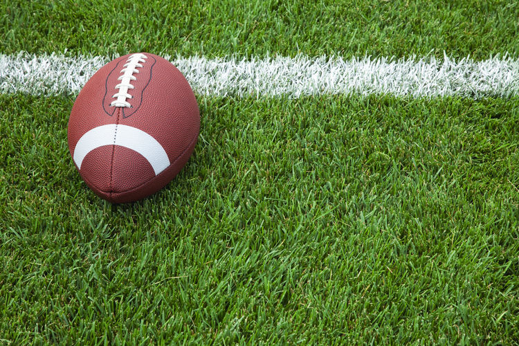 American football ball at the edge on playing field