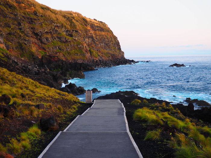Scenic view of road by sea against sky