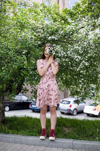 Full length of young woman standing against trees